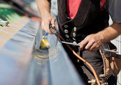 Dachdecker montiert Dachrinnen